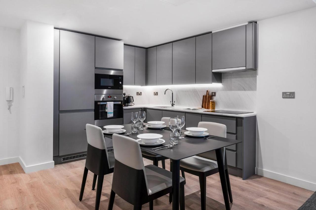 Citysuites 2 Aparthotel Manchester Esterno foto The photo shows a modern kitchen and dining area. The kitchen features sleek, gray cabinetry and a countertop that complements the overall aesthetic. There are built-in appliances, including an oven and refrigerator, arranged neatly. Next to the kitc