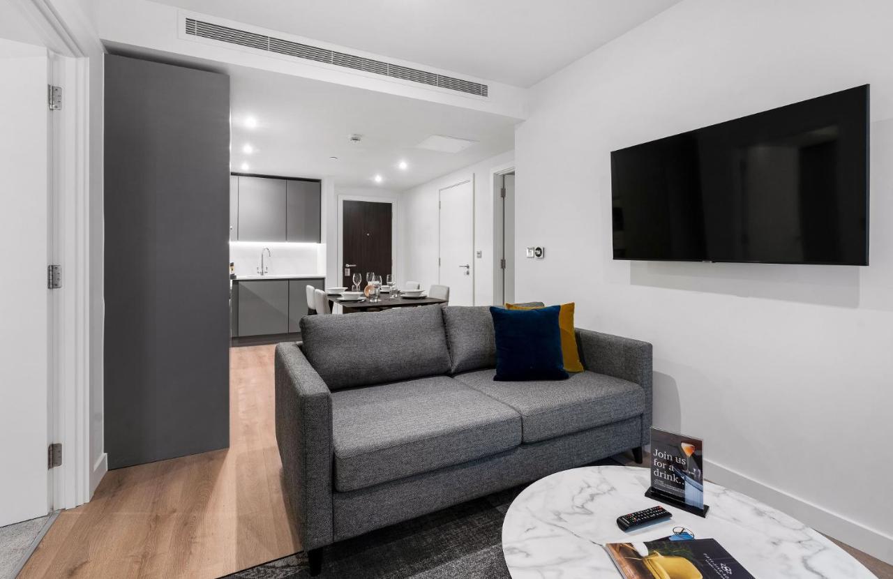 Citysuites 2 Aparthotel Manchester Esterno foto The photo shows a modern living space that includes a gray sofa with colorful cushions, a round marble coffee table, and a flat-screen TV mounted on the wall. In the background, there is a kitchen area featuring sleek cabinets. The flooring is light 
