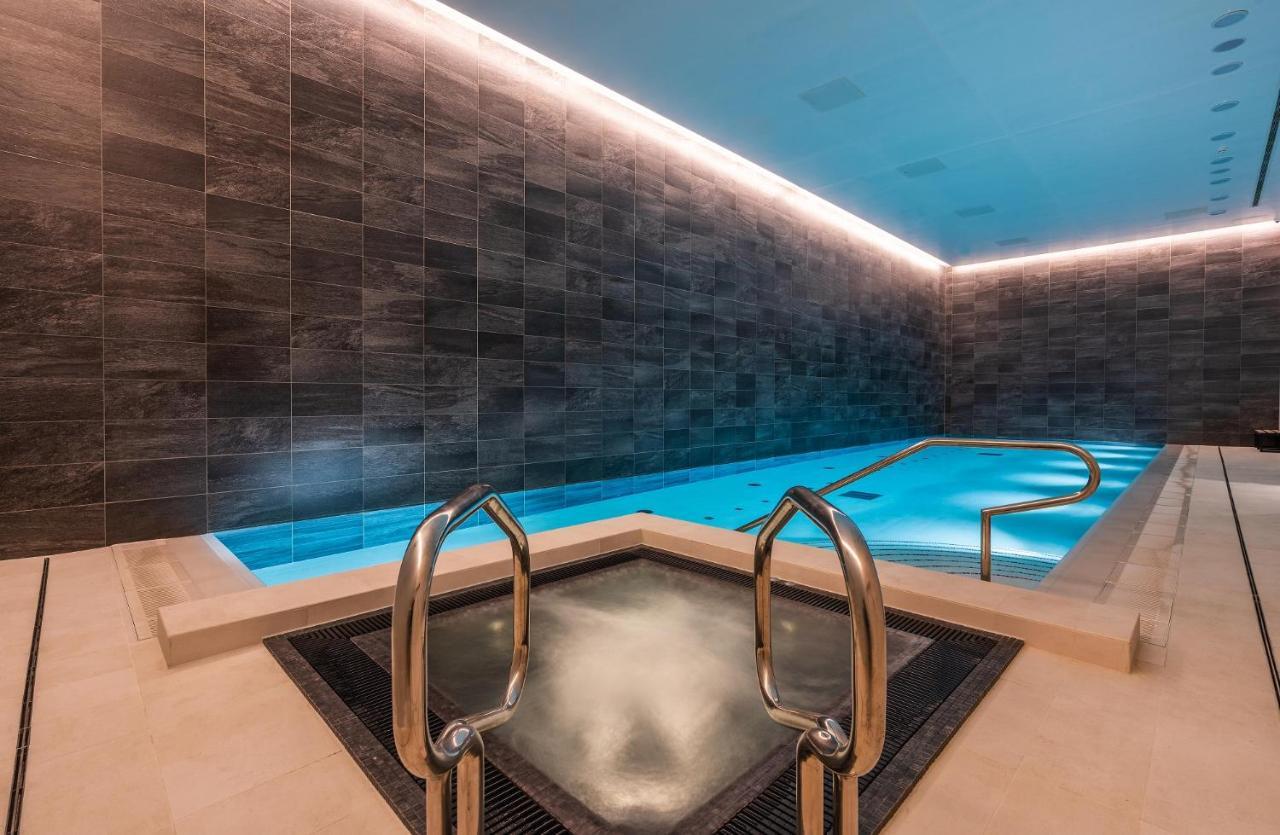 Citysuites 2 Aparthotel Manchester Esterno foto The photo shows a modern indoor swimming pool area. The pool features a sleek, rectangular design with a beautiful blue water that seems illuminated. Surrounding the pool are dark, textured walls, adding to the elegant atmosphere. There are dual meta