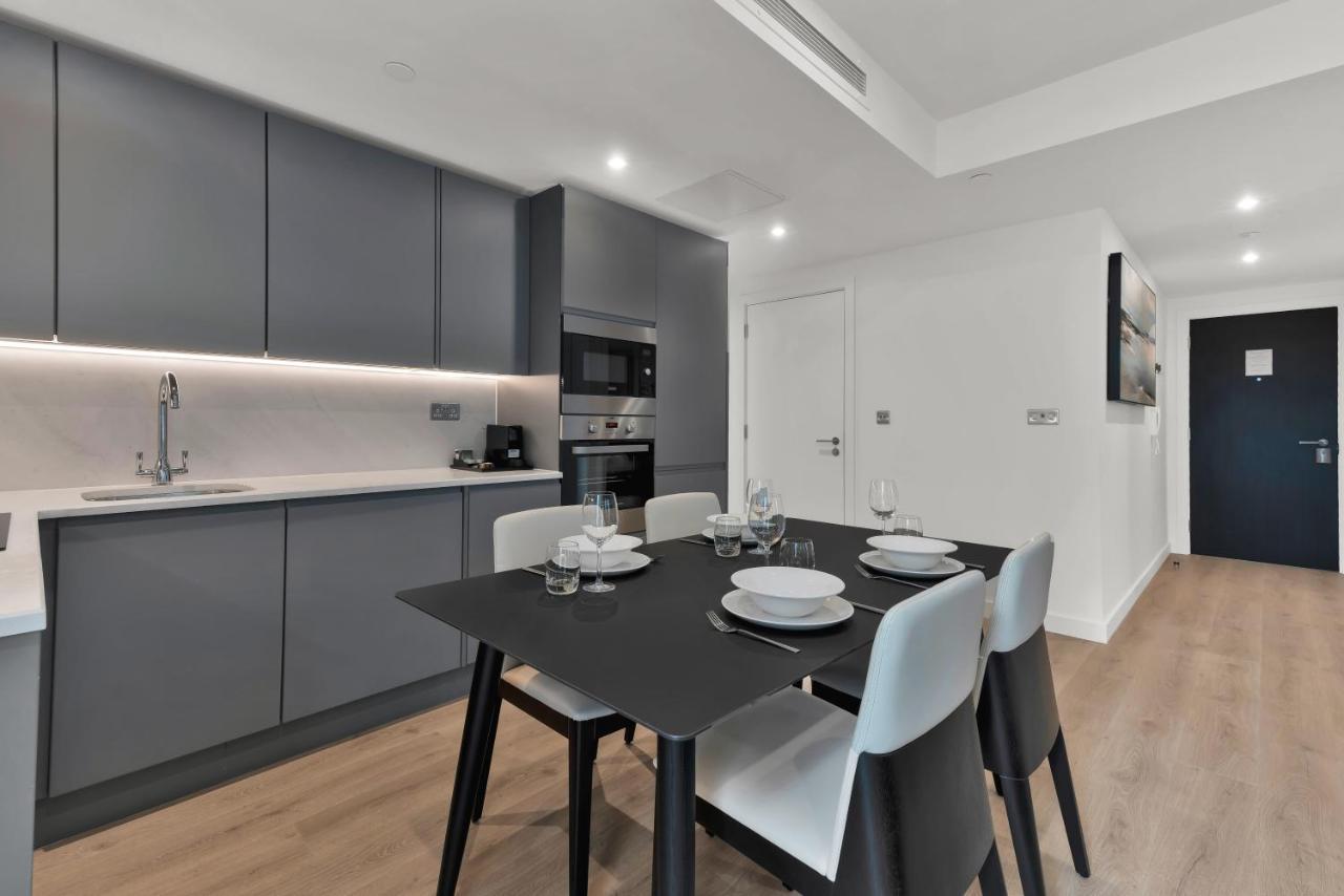 Citysuites 2 Aparthotel Salford  Esterno foto The photo shows a modern kitchen and dining area. There are sleek gray cabinetry and countertops, with a built-in oven and microwave. The kitchen is well-lit, featuring under-cabinet lighting that adds to the contemporary feel. In the dining area, th