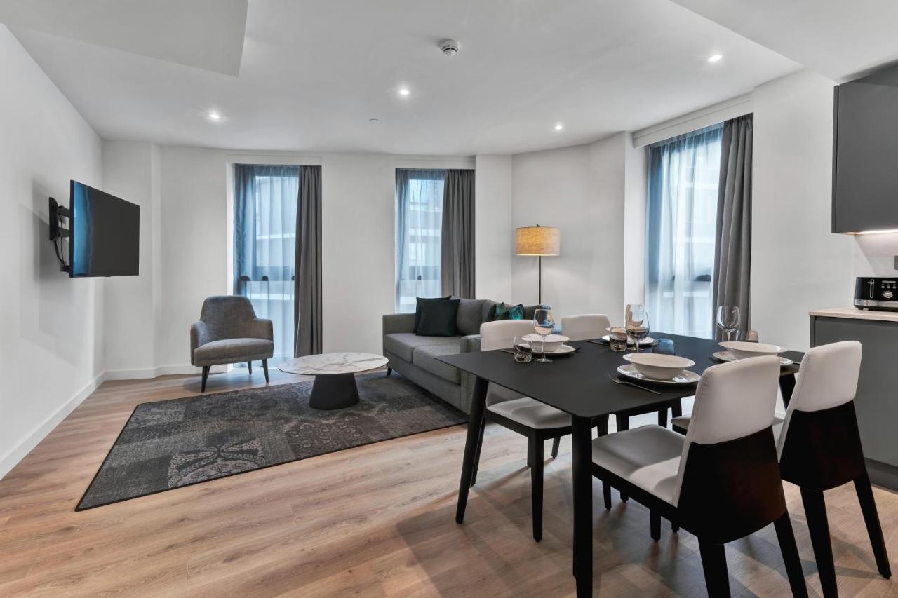 Citysuites 2 Aparthotel Manchester Esterno foto The photo shows a modern living space that includes a living area and dining area. 

- **Living Area**: There's a gray sofa with a coffee table in front of it, along with a single armchair. A large flat-screen TV is mounted on the wall. The space is 