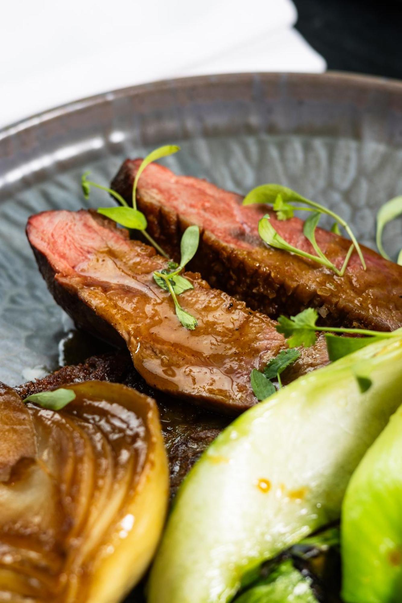 Citysuites 2 Aparthotel Manchester Esterno foto The photo features slices of meat, likely beef, presented on a decorative plate. The meat appears to have a rich brown sauce drizzled over it and is garnished with fresh herbs, adding a pop of green. There are also some slices of a light-colored vege